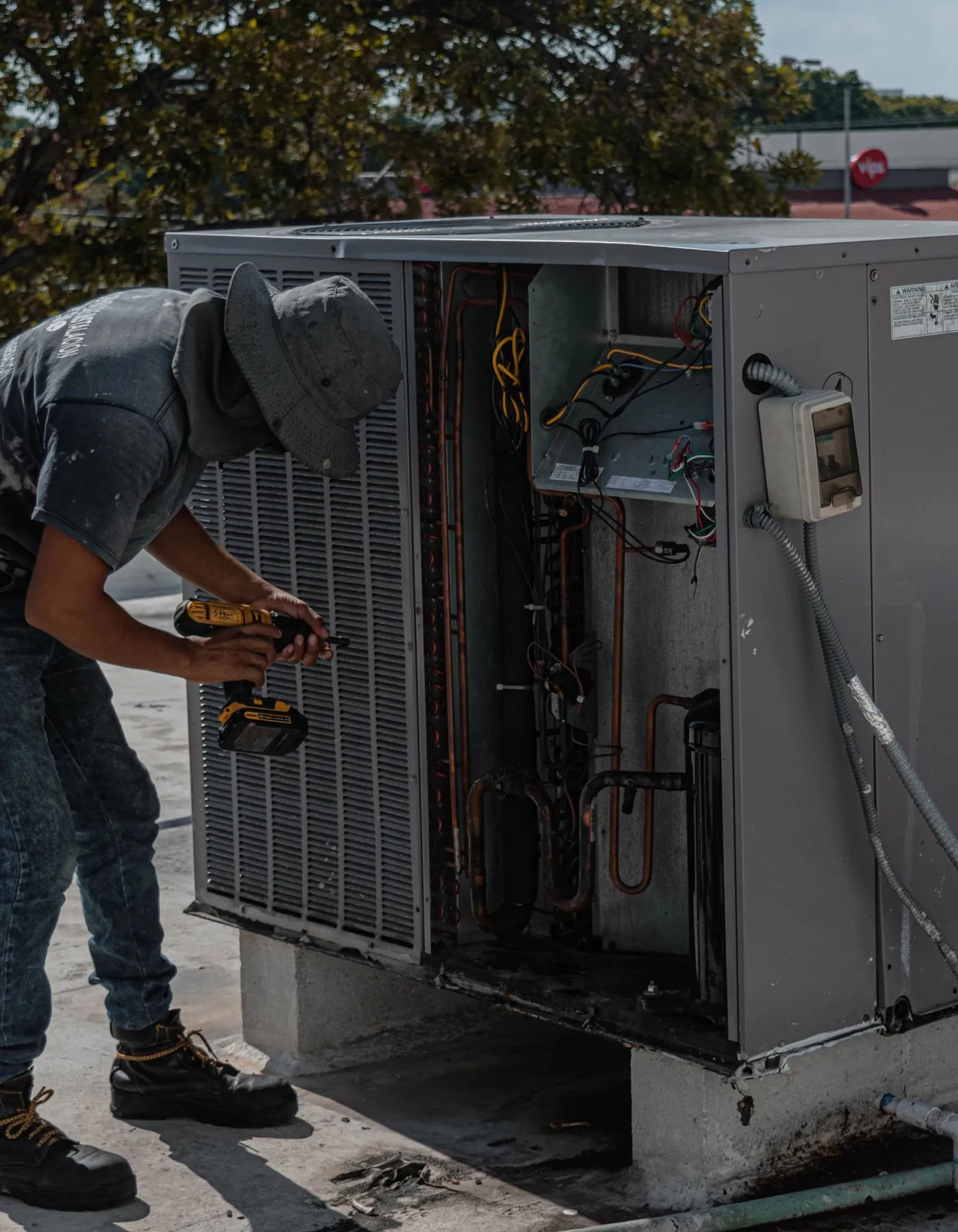 A technician servicing a rooftop air conditioning unit