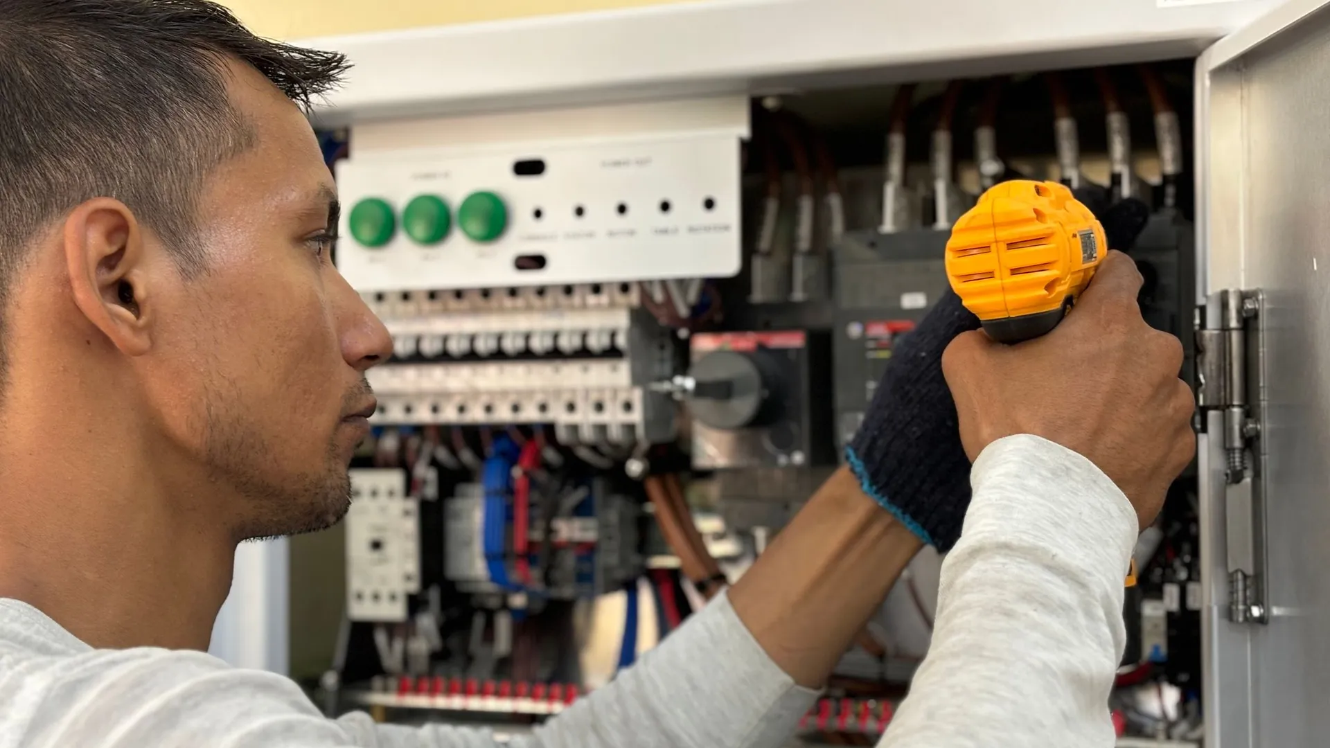 Hands working inside an electrical panel